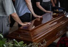 Hollywood Icon’s Final Power Move Mourners with hands on a polished wooden casket