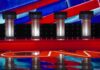 Debate Standoff Explodes – Where’s Talarico? Debate stage with four empty podiums and bright red and blue backdrop