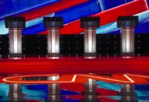 Debate Standoff Explodes – Where’s Talarico? Debate stage with four empty podiums and bright red and blue backdrop