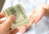 Hand giving a stack of US dollar bills
