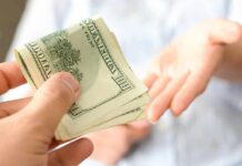 Tariff Math Explodes $5,000 Promise Hand giving a stack of US dollar bills
