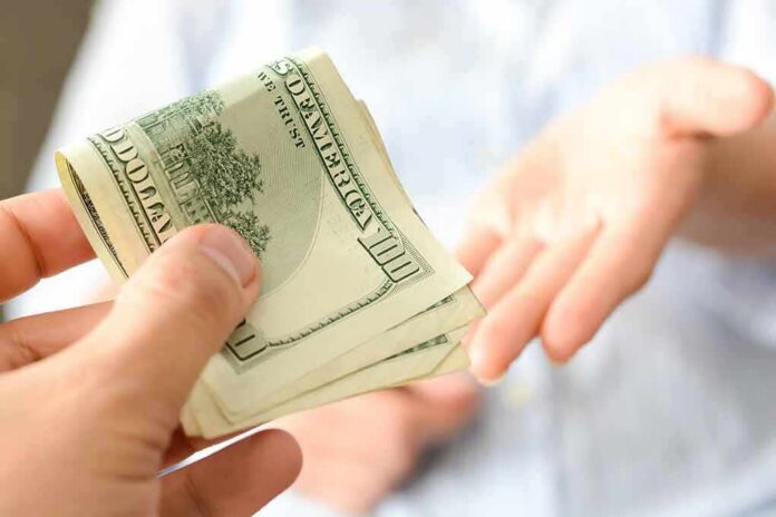Hand giving a stack of US dollar bills