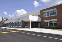 Hero Chases Gunman Into Classrooms Modern school building with large windows and a clear sky