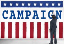 Staggering $64M Scrambles Texas Map Man in suit writing on large campaign banner with stars and stripes